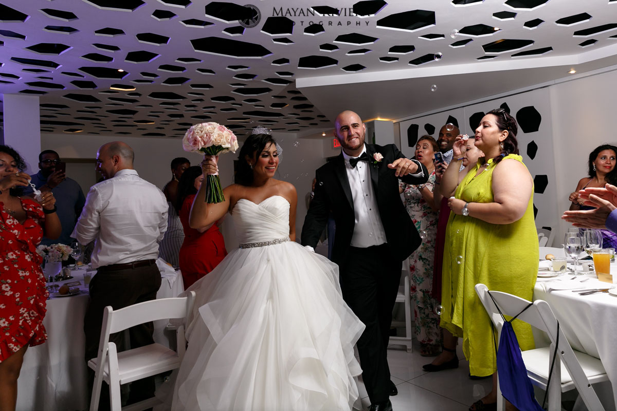 NewlywedsWalkIntoReceptionInBubbleShower