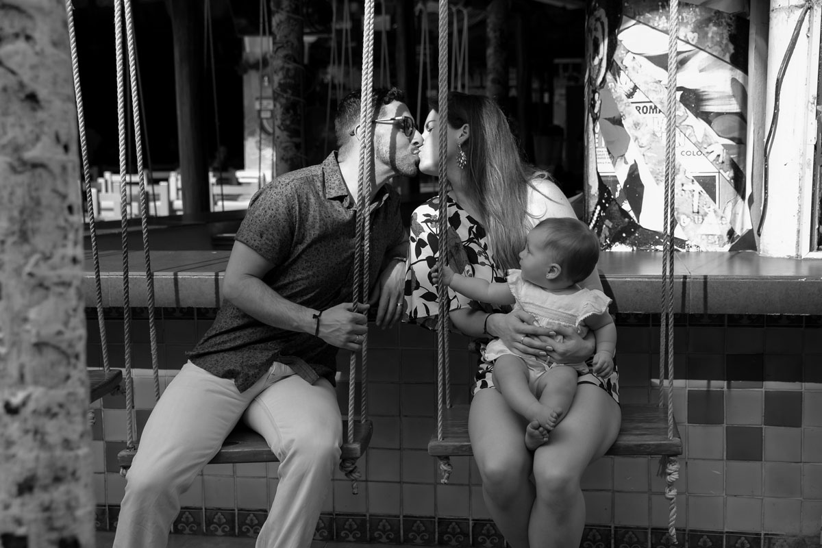 ParentsKissOnBarSwingHoldingBaby