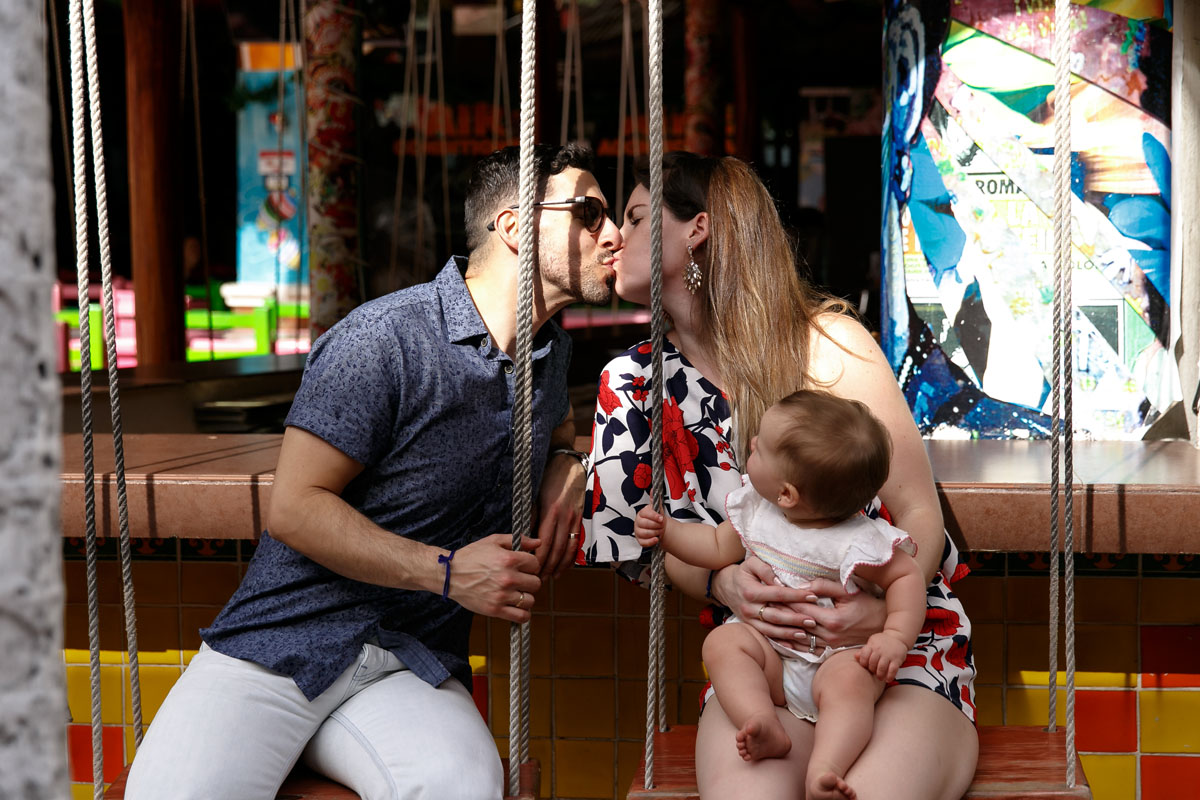 ParentsKissOnBarSwingHoldingBaby