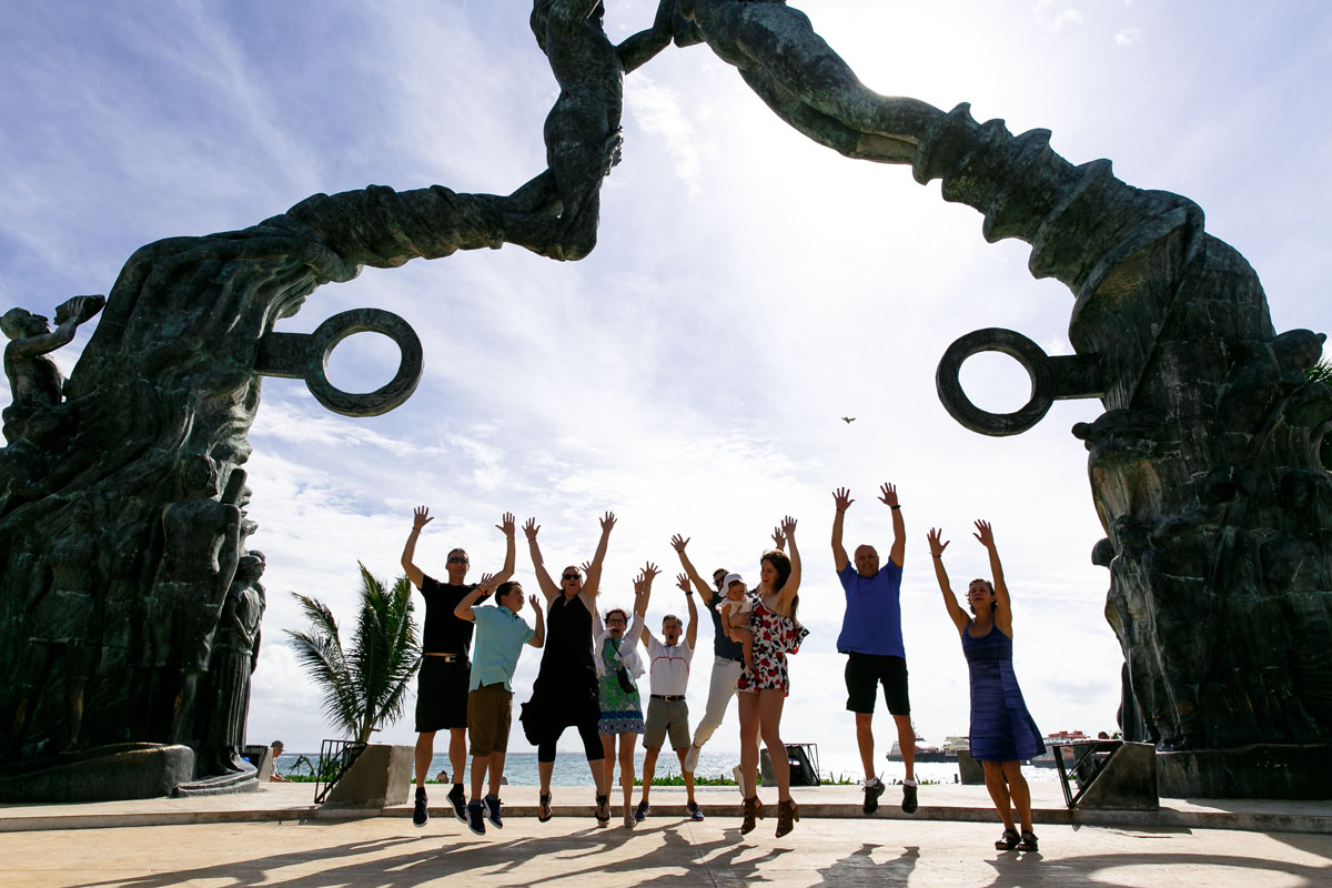ExtendedFamilyJumpsForJoyUnderBeachStatue