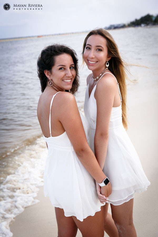 SmilingSistersPoseTogetherOnBeachHoldingHands