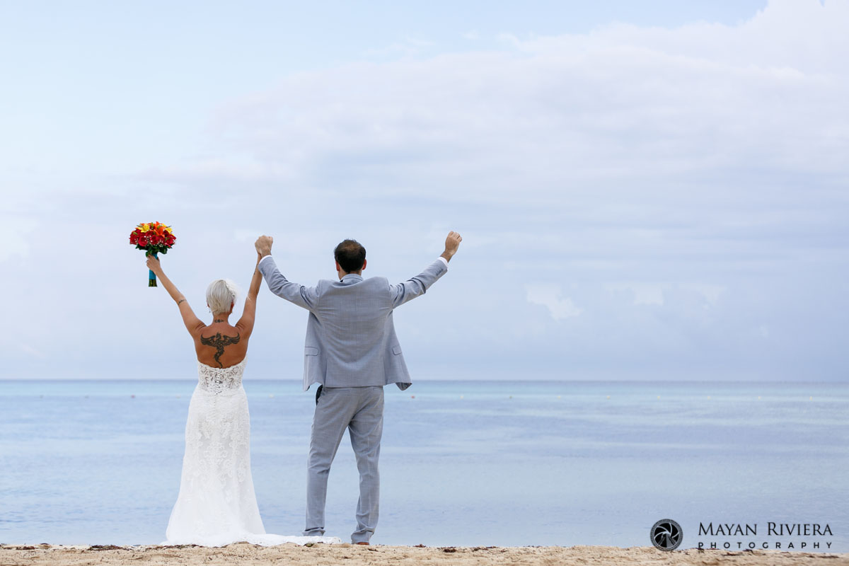 CheeringNewlywedsOnBeachLookingOutToSea