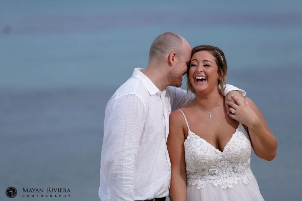 LaughingNewlywedsEmbraceOnBeach