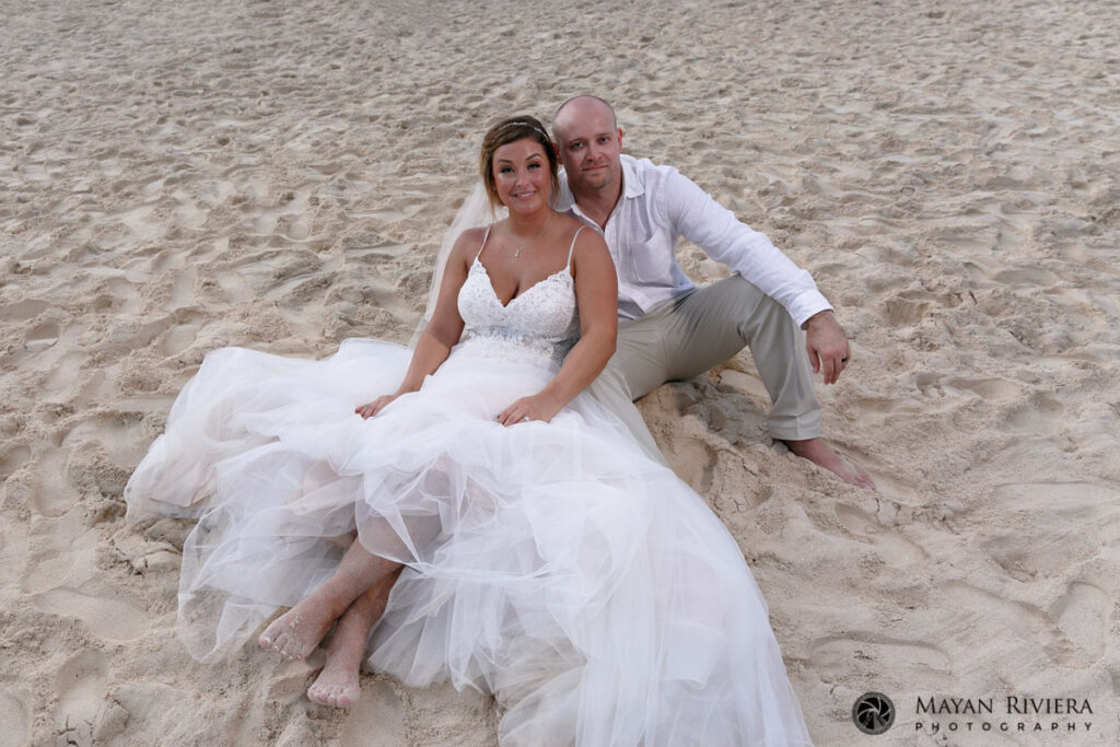 NewlywedsSitOnBeachLookingUp