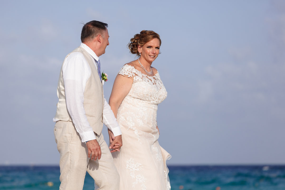NewlywedsOnBeachwalkHoldingHands