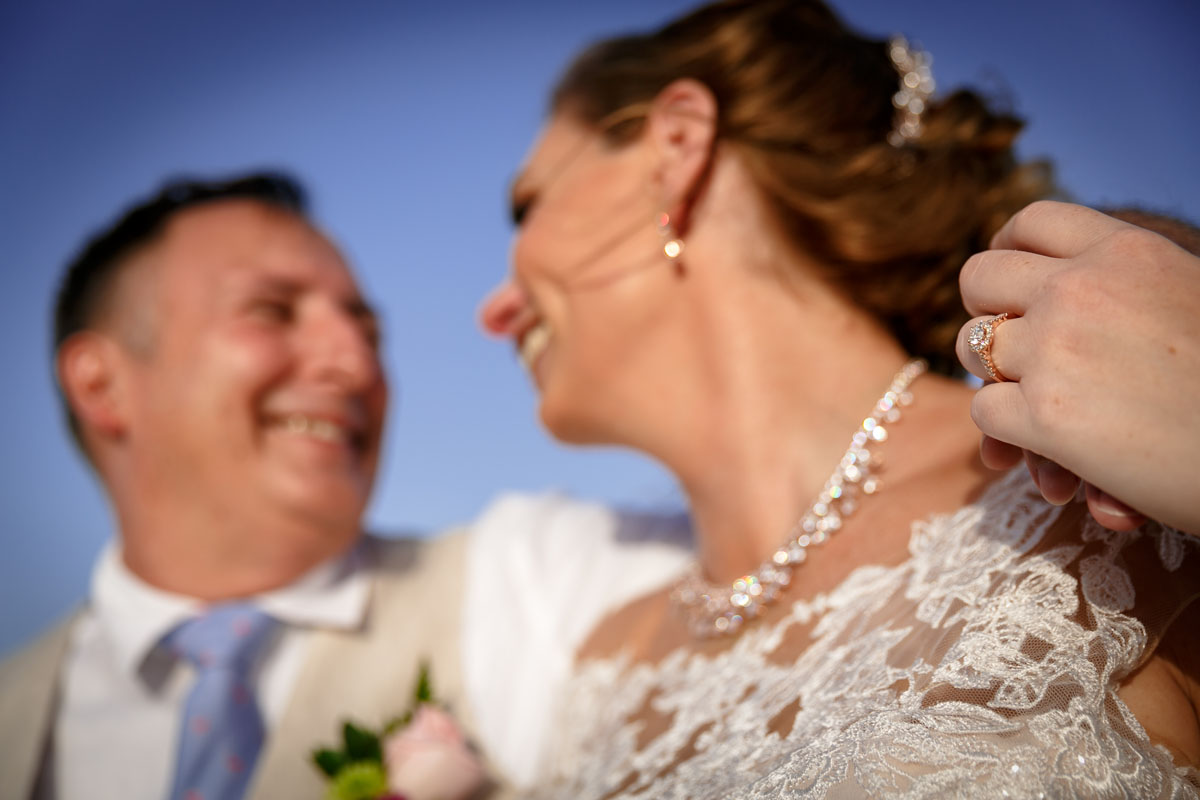 NewlywedsPoseOnBeachShowingRing