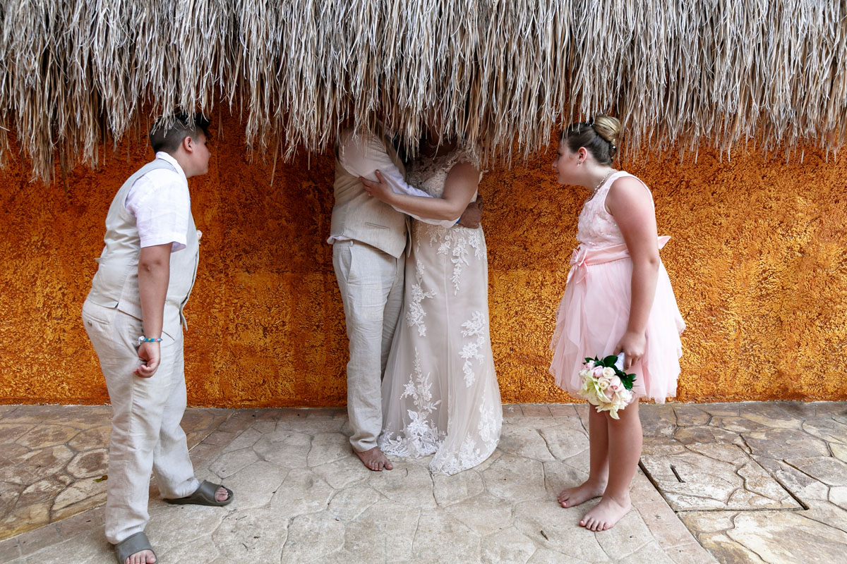 KidsPeekUnderPalapaWhileNewlywedsKiss