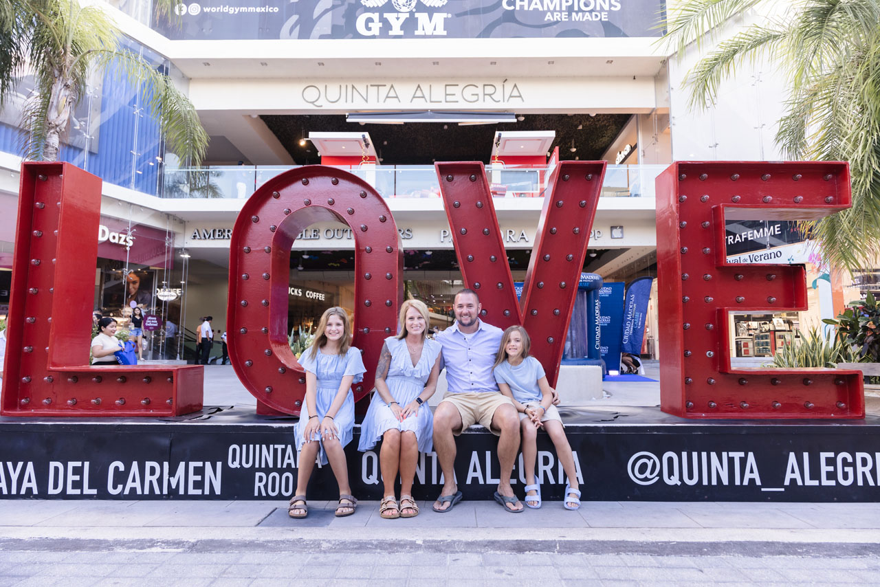 Happy family sits together in front of Love sign