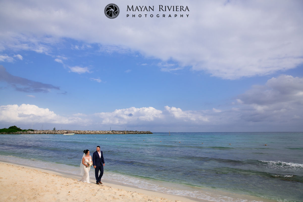 Newlyweds walk beach under stormy skies