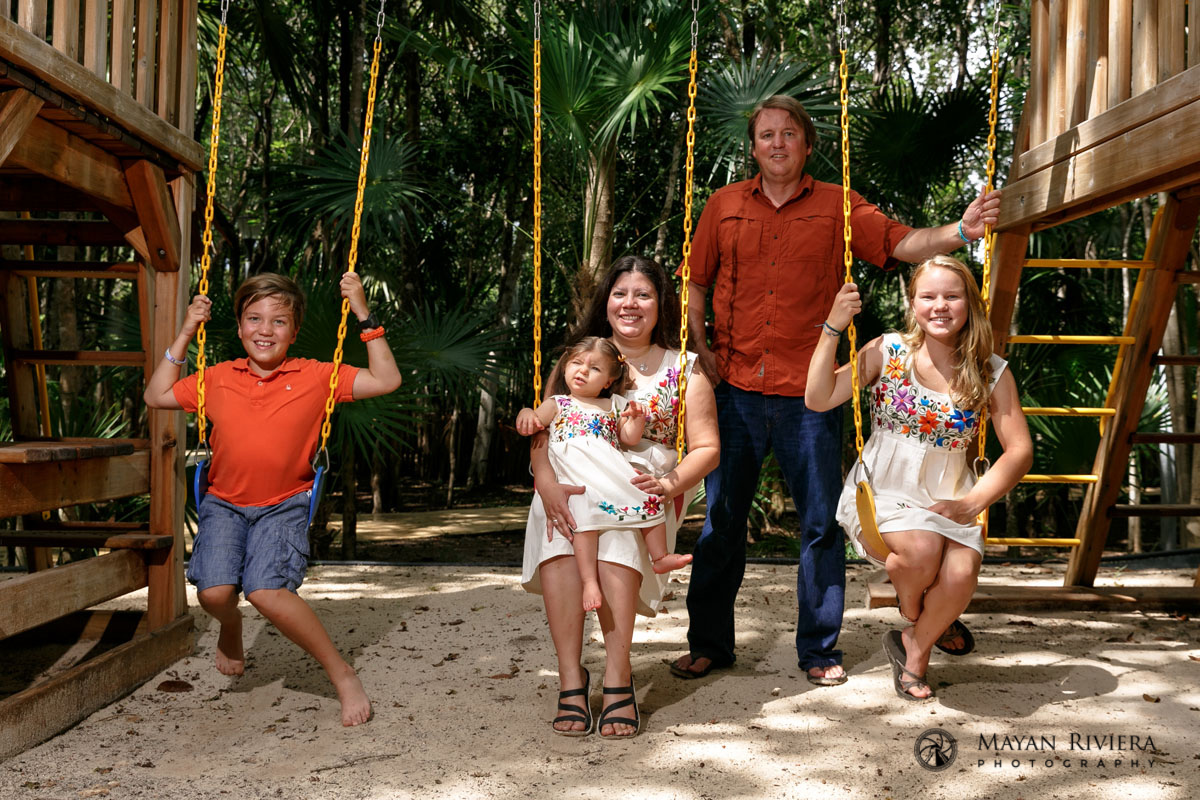 Saras family pose on swings in the playground