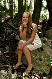 SaraSitsOnCenoteRockInJungle