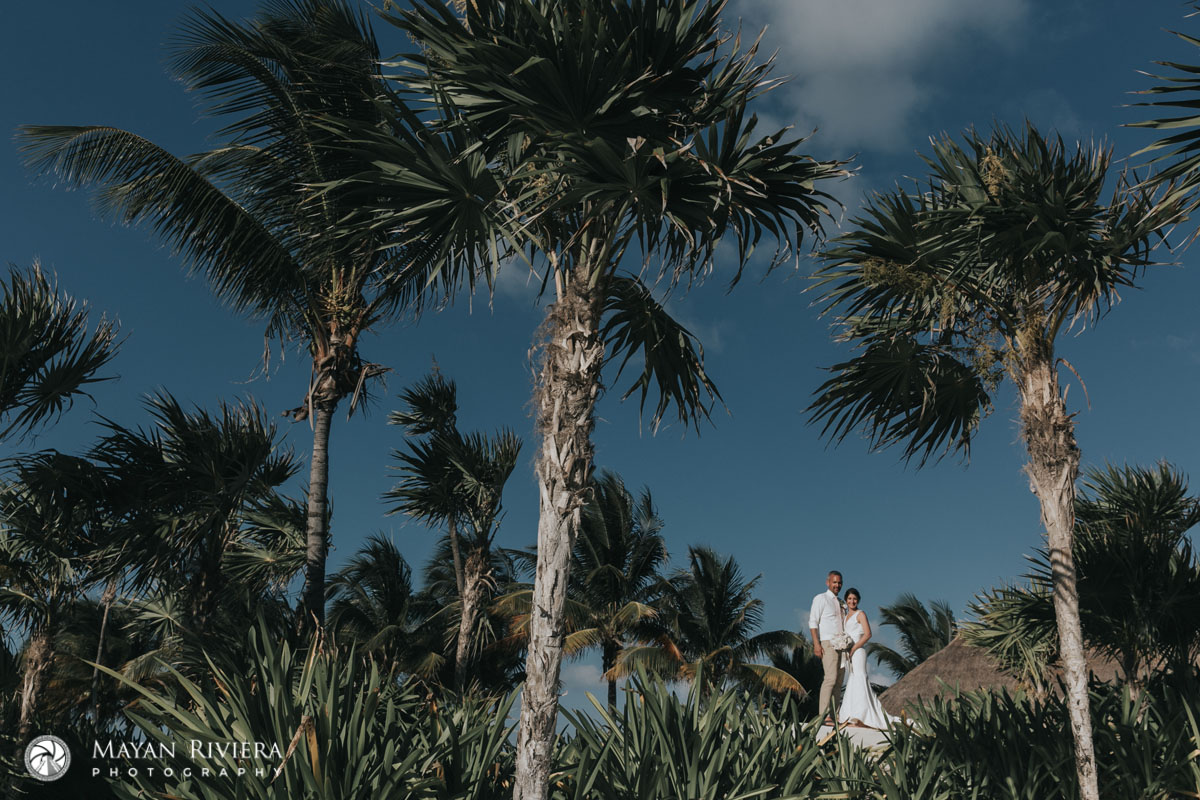 NewlywedsPoseOnBeachLookingThruJungle