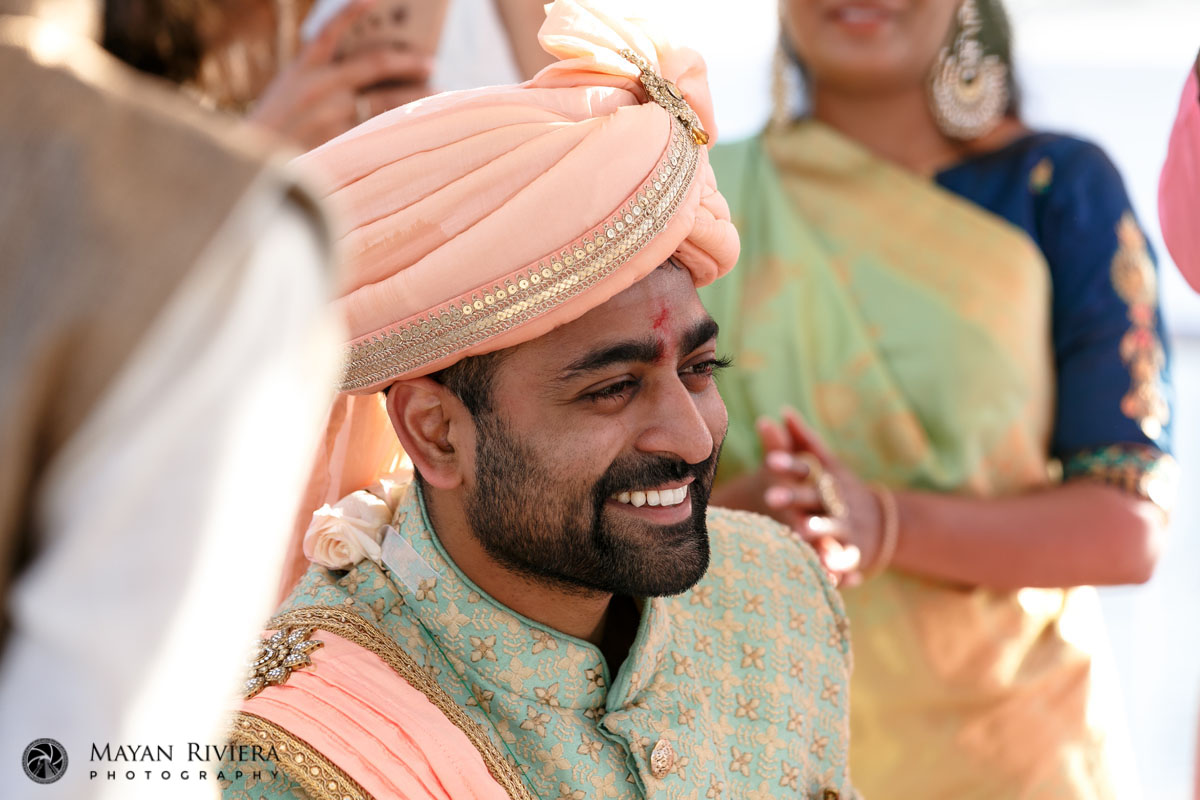 SmilingHinduGroomSitsBehindCurtainShield