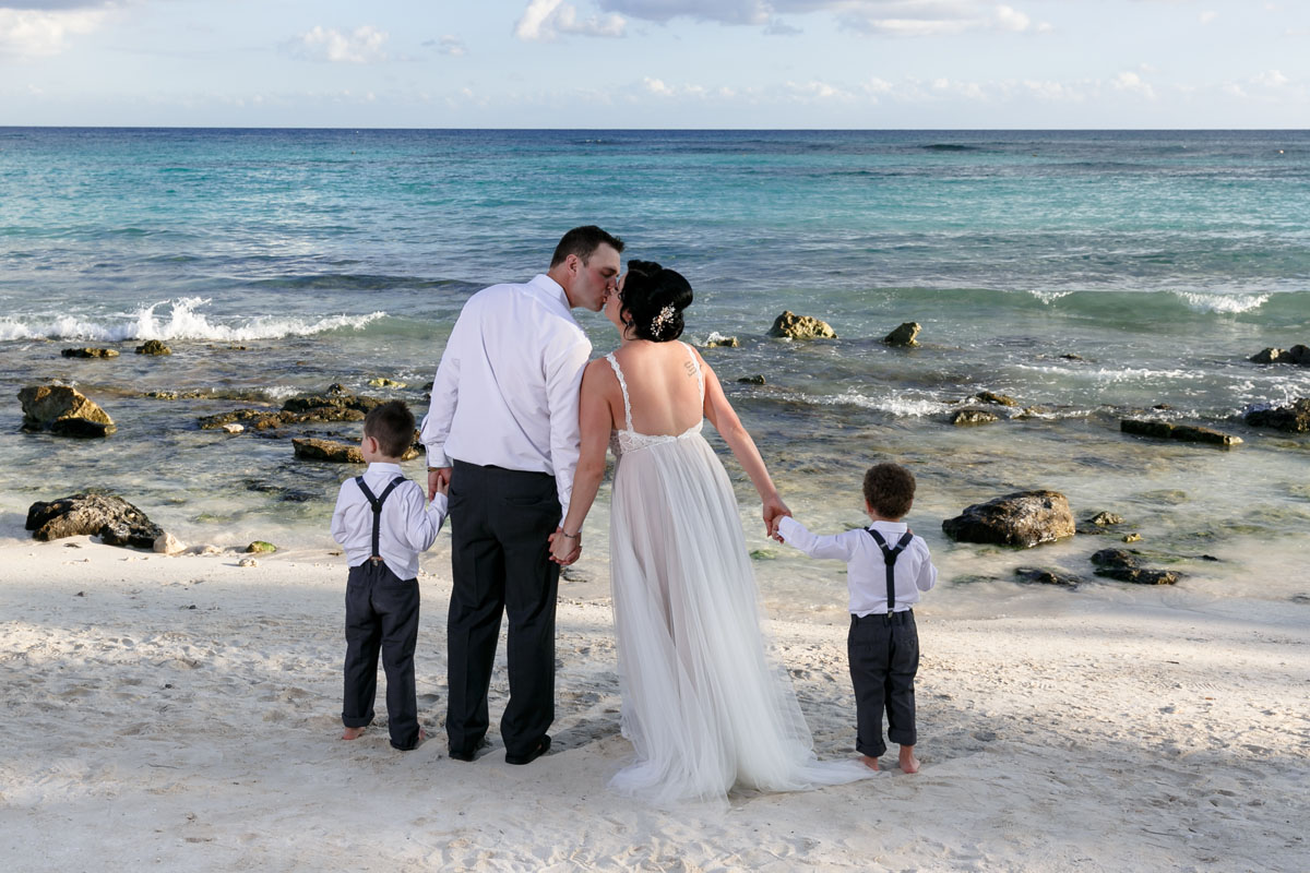 NewlywedsKissHoldingSonsHands