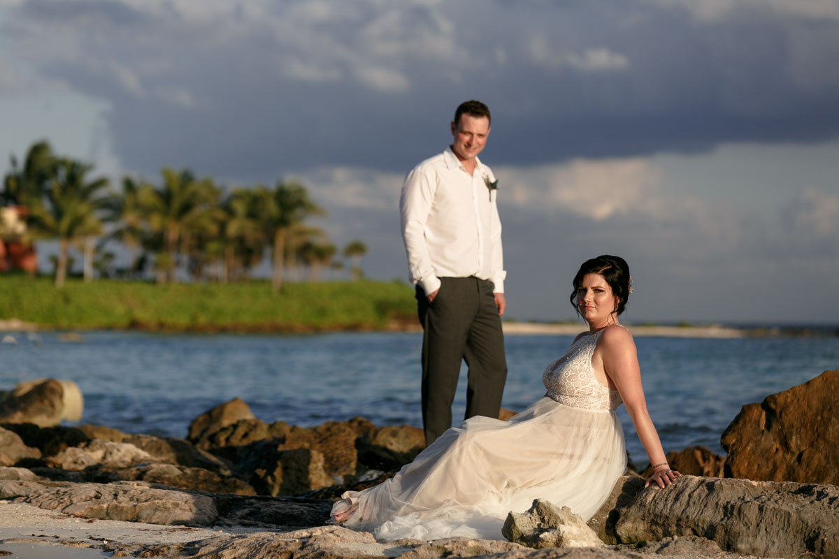 NewlywedsPoseOnBeachRocks