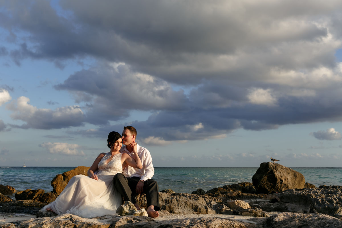 NewlywedsPoseOnBeachRocks