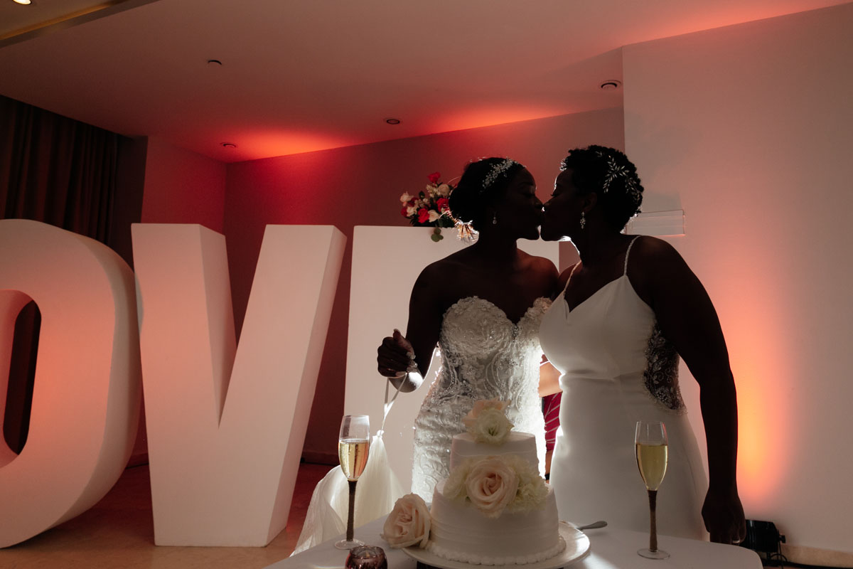 Newlyweds kiss after sharing a bite of wedding cake