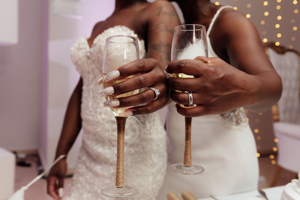 NewlywedsShowRingsHoldingChampagneToast