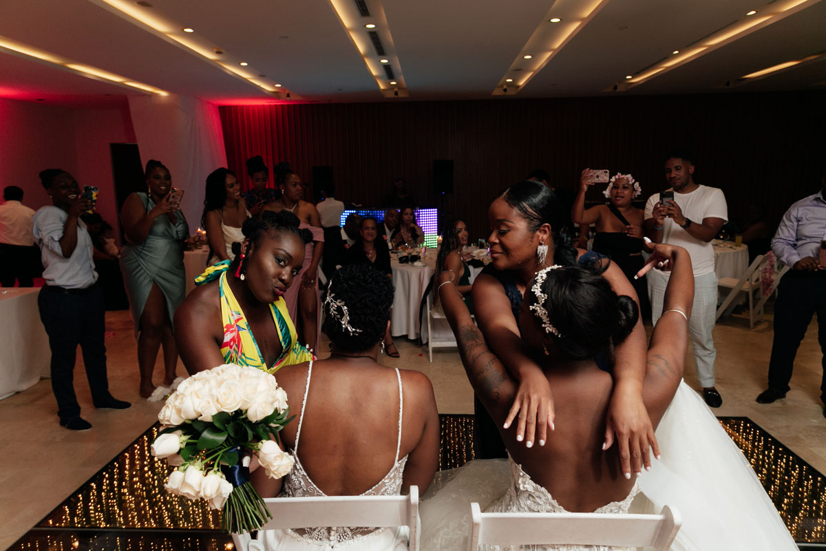 NewlywedsSeatedOnDanceFloorGetHugs