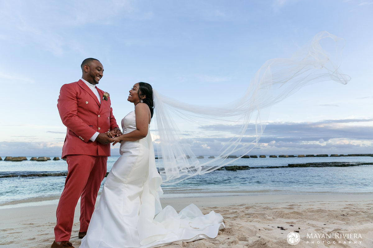 NewlywedsPoseOnBeachWithBillowingVeil