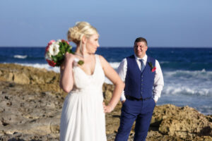 NewlywedsPoseOnBeachRocks