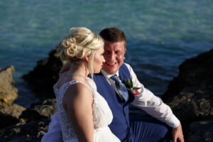 NewlywedsPoseOnBeachRocks