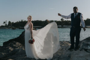 NewlywedsPoseOnBeachRocks