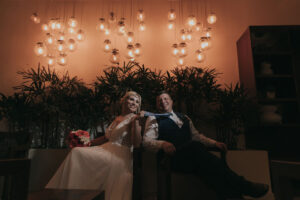 NewlywedsPosePlayfullyByGoldenLights