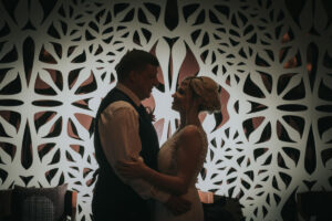 NewlywedsPoseShilouettedByWallArt