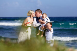 NewlywedsKissWithSonsOnBeach