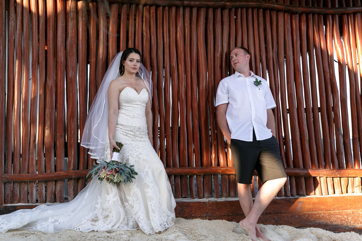 NewlywedsPoseByReedWall