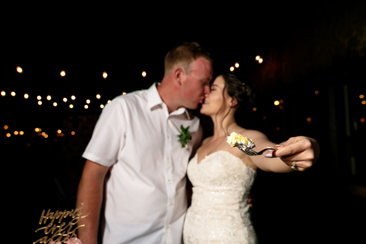 NewlywedsKissHoldingCakeBite