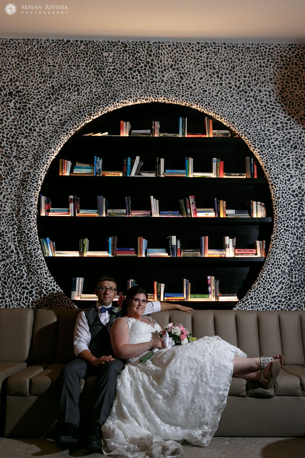 NewlywedsPoseOnCouchByBookshelf