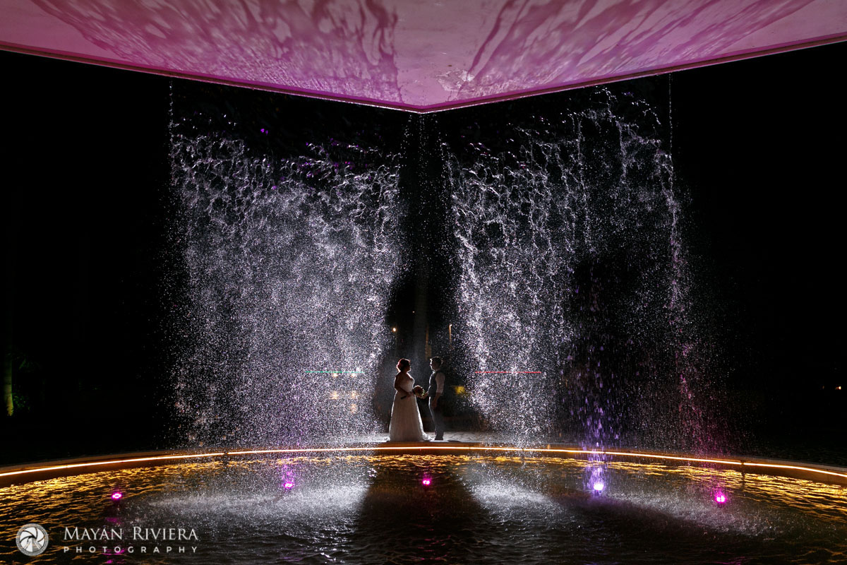 NewlywedsPoseBehindPoolWithWaterFall