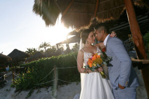 NewlywedsEmbraceUnderPalapa