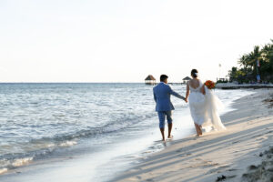 NewlywedsHoldHandsOnBeachwalk