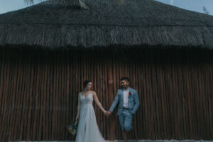 NewlywedsHoldHandsByWall