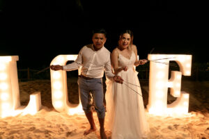 NewlywedsHoldSparklersByLoveSign