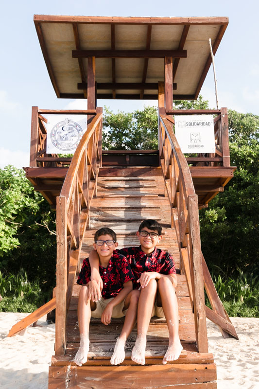 BoysSitOnLifeGuardTowerStepsWithArmsAroundEachOther