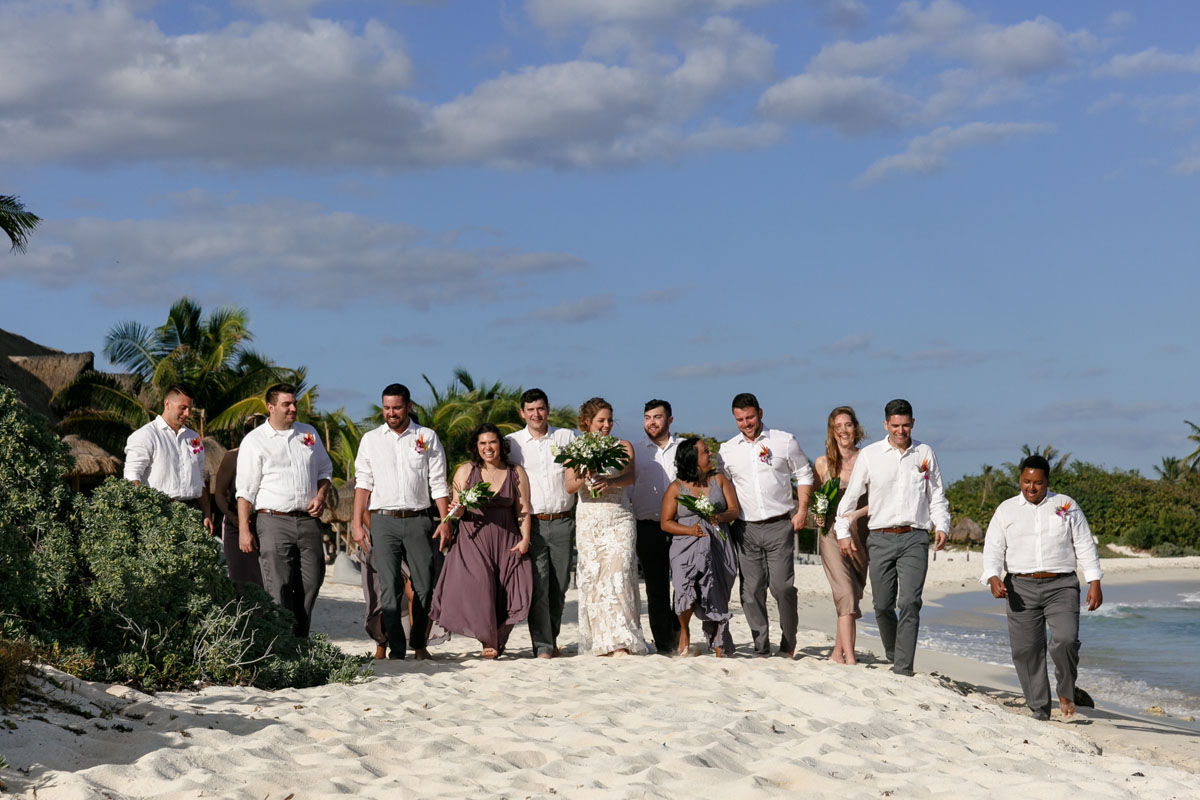 NewlywedsOnBeachWalkWithWeddingParty