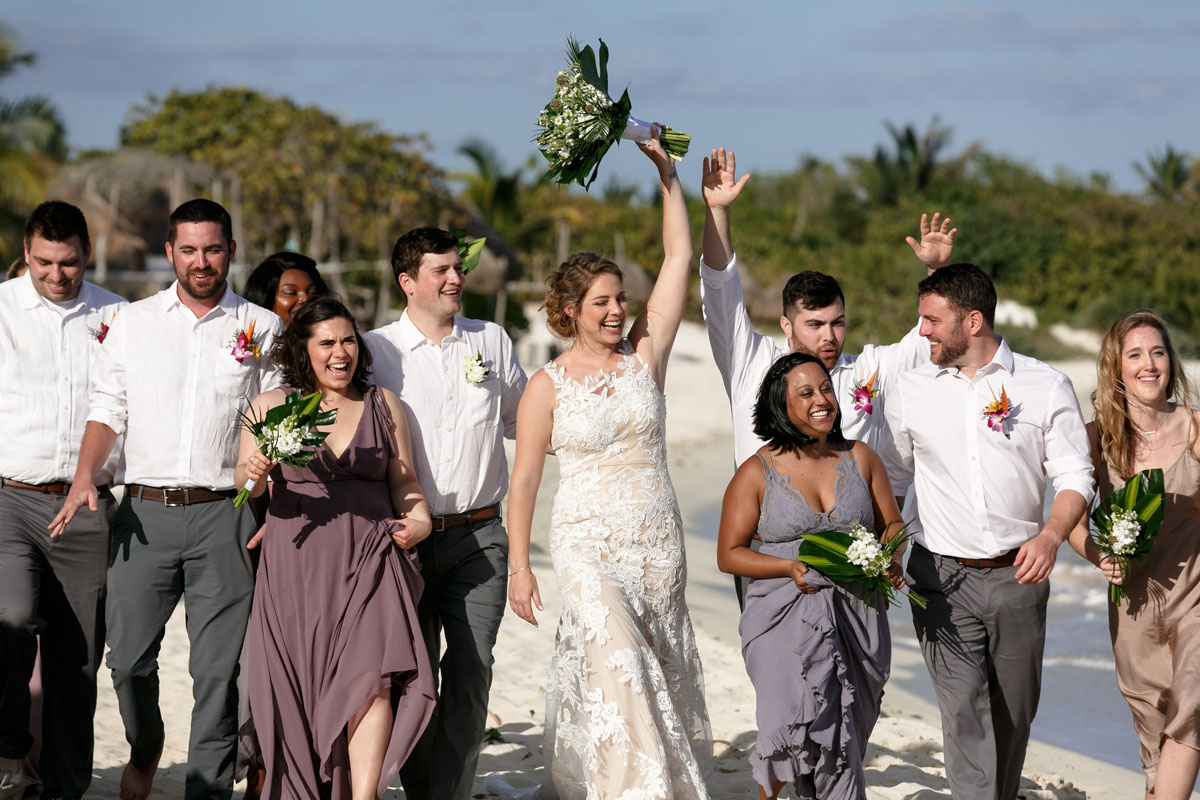 NewlywedsOnBeachWalkWithWeddingParty