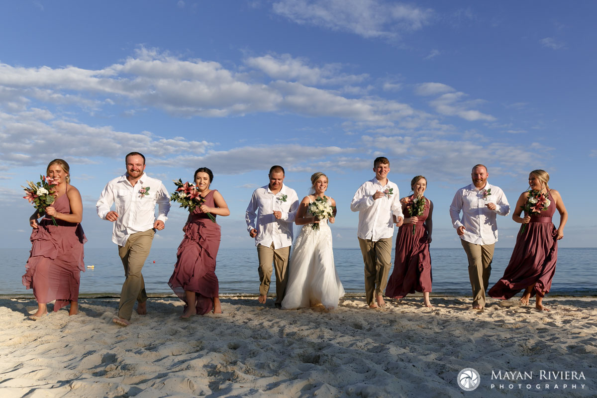 NewlywedsRunWithAttendantsOnBeach