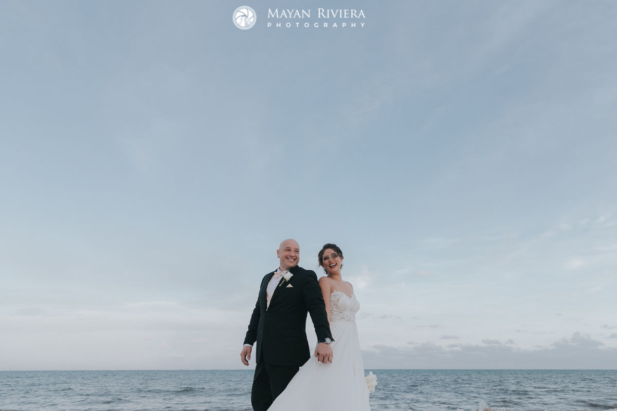 LaughingNewlywedsHoldHandsOnBeach