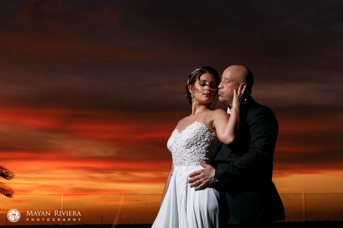 NewlywedsEmbraceShilouettedBySpectacularSunset