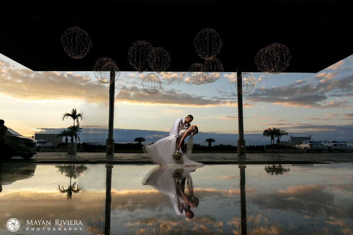 Royalton newlyweds dip in a kiss, reflected in the golden sunset