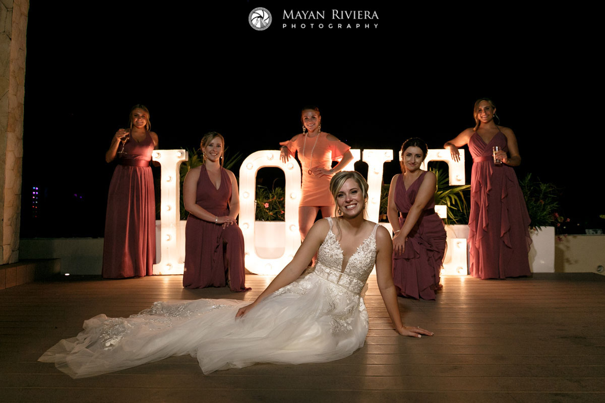 BrideSitsInFrontOfLoveSignWithBesties