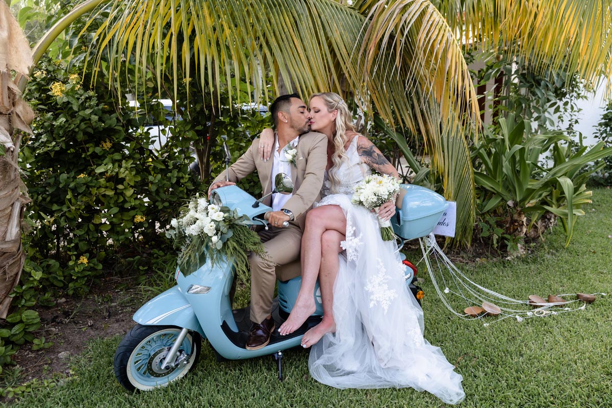Wedding couple kiss sitting on their going away moto