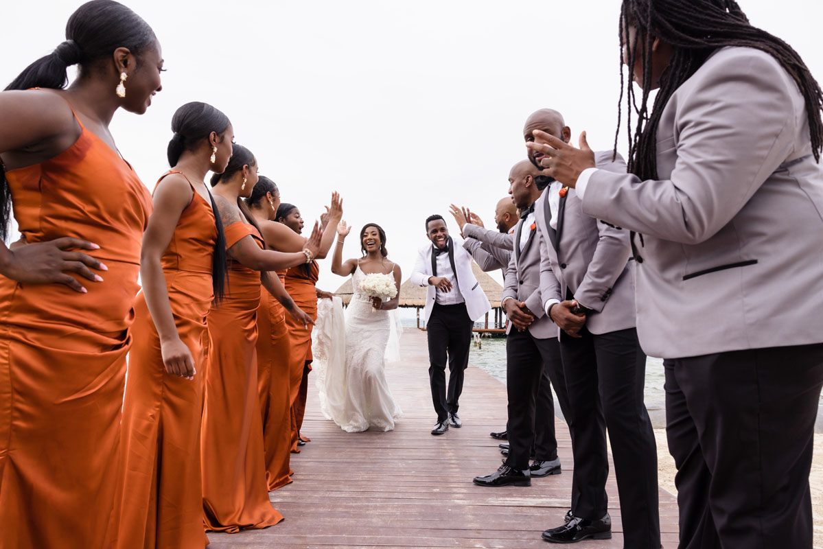 Cheering newlyweds walk attendant gauntlet