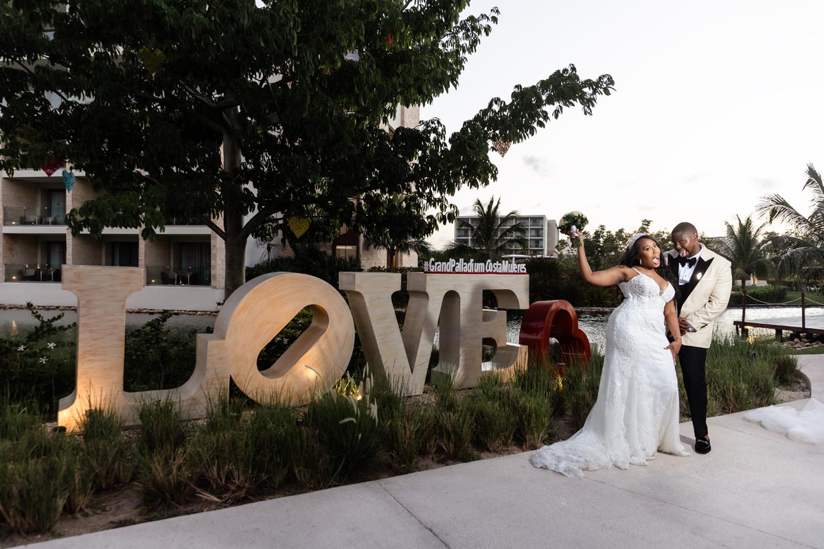 Newlyweds clown in front of Love Sign