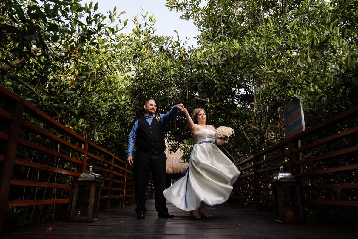 Newlyweds dance twirling on wooden pathway